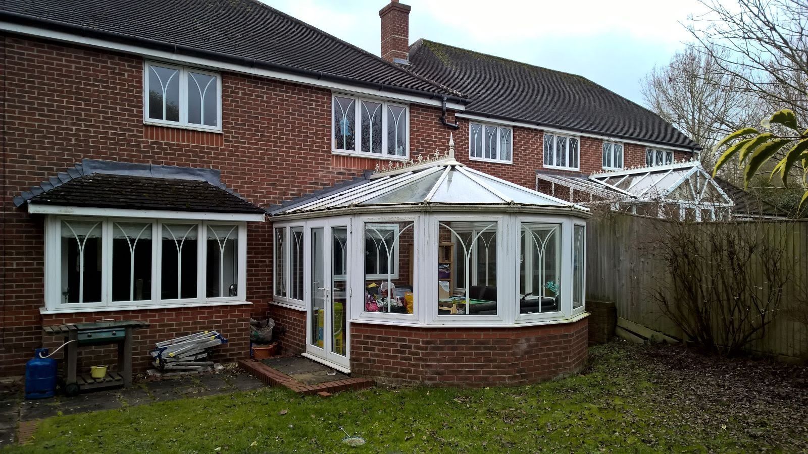 A brick house with a conservatory in the backyard.