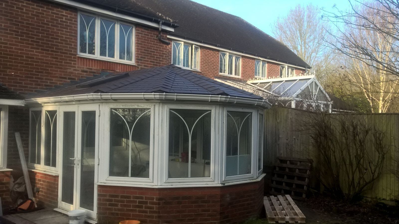 A brick house with a white conservatory on the side of it.