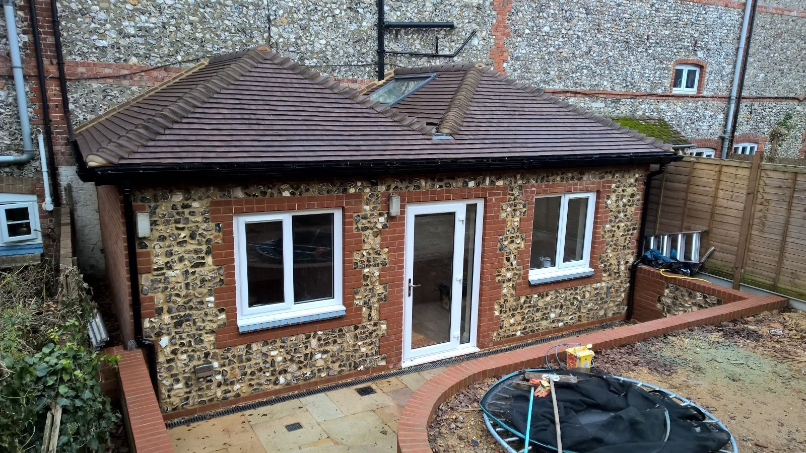 A small brick house with a trampoline in the backyard.
