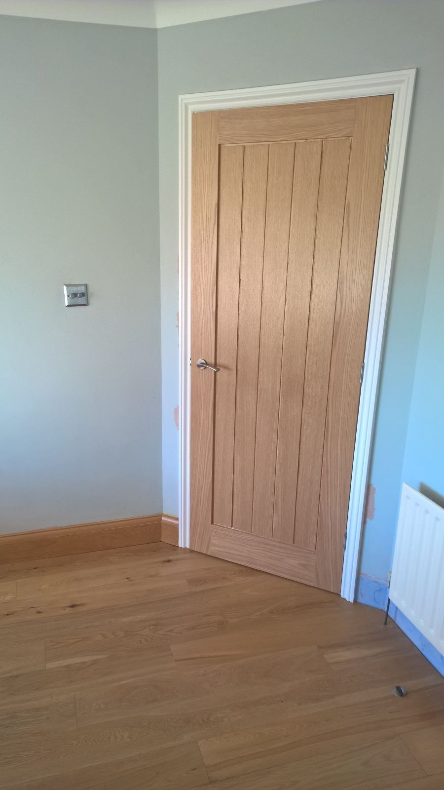 An empty room with a wooden door and a radiator.