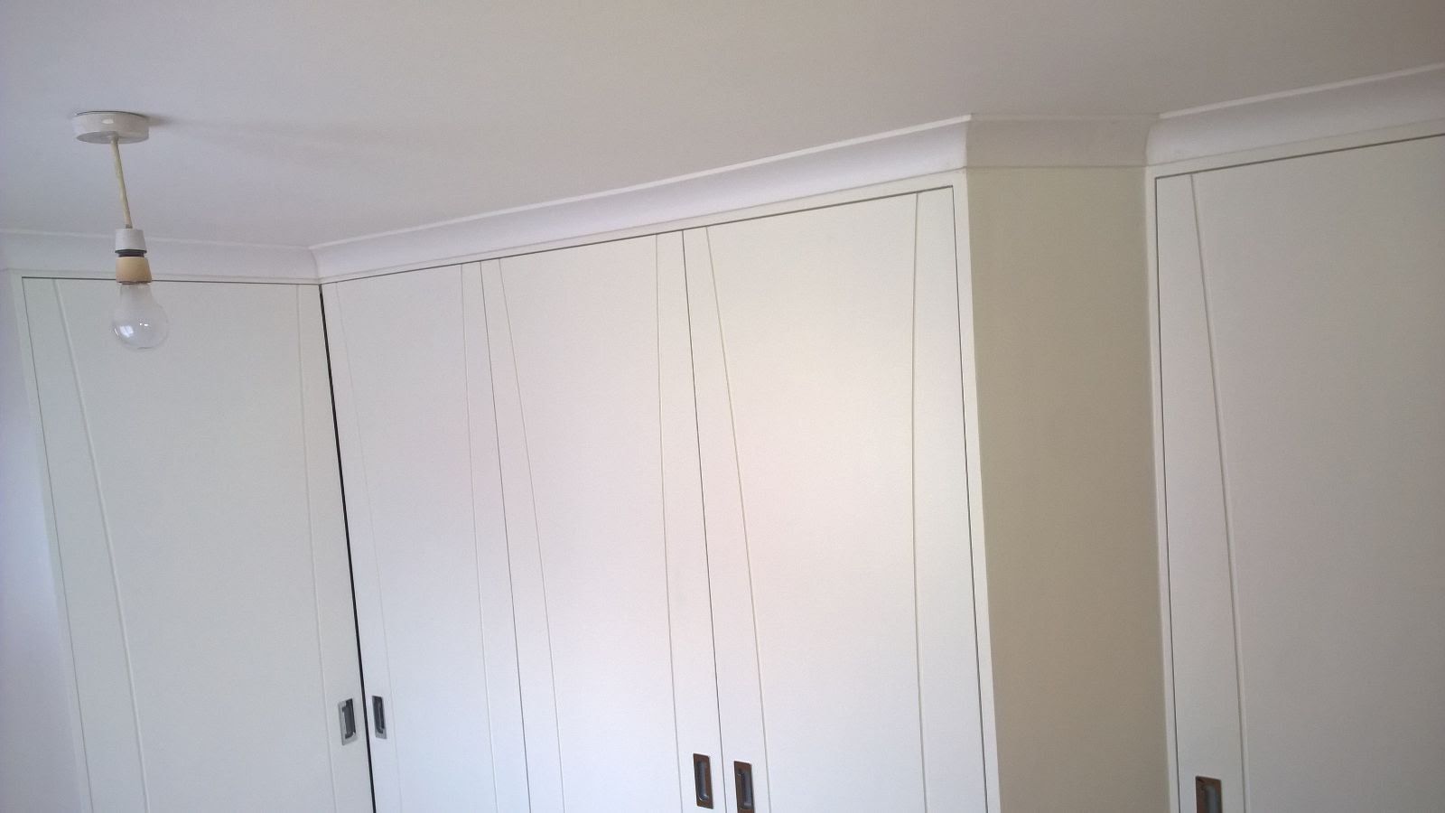 A room with white cabinets and a light hanging from the ceiling.