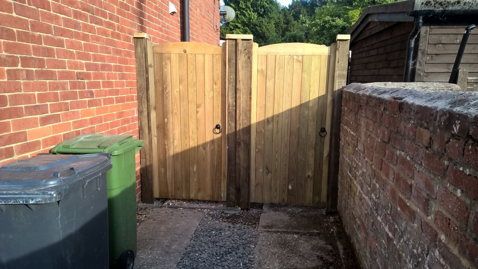 A wooden gate is sitting next to a brick wall.