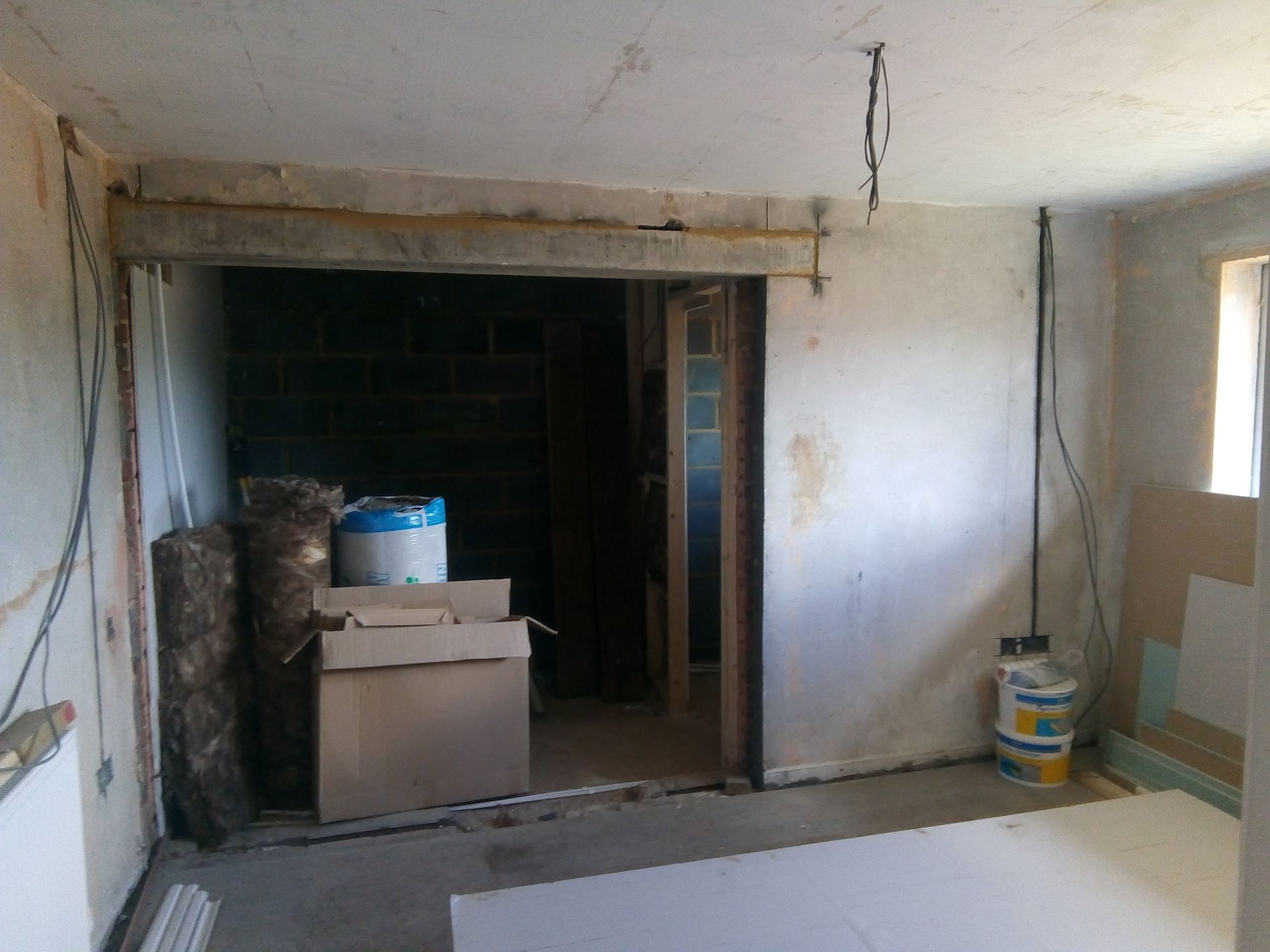 An empty room with boxes and buckets on the floor