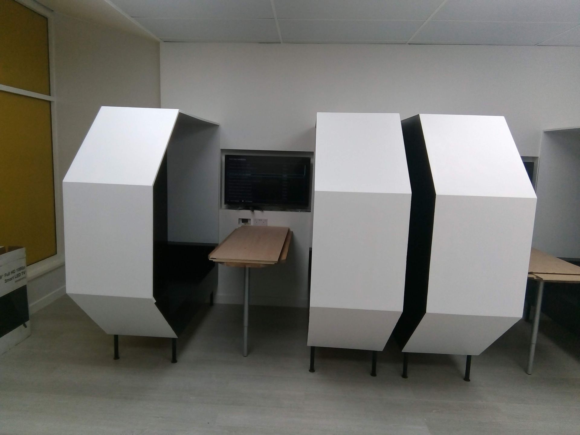 A room with three cubicles and a table in it