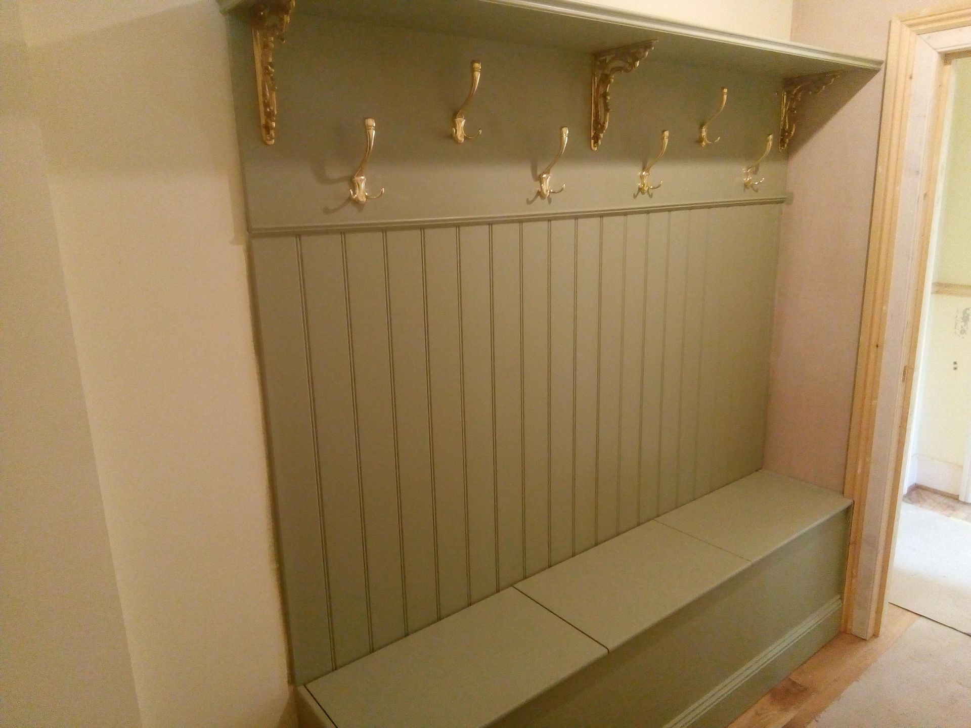 A hallway with a bench and hooks on the wall.