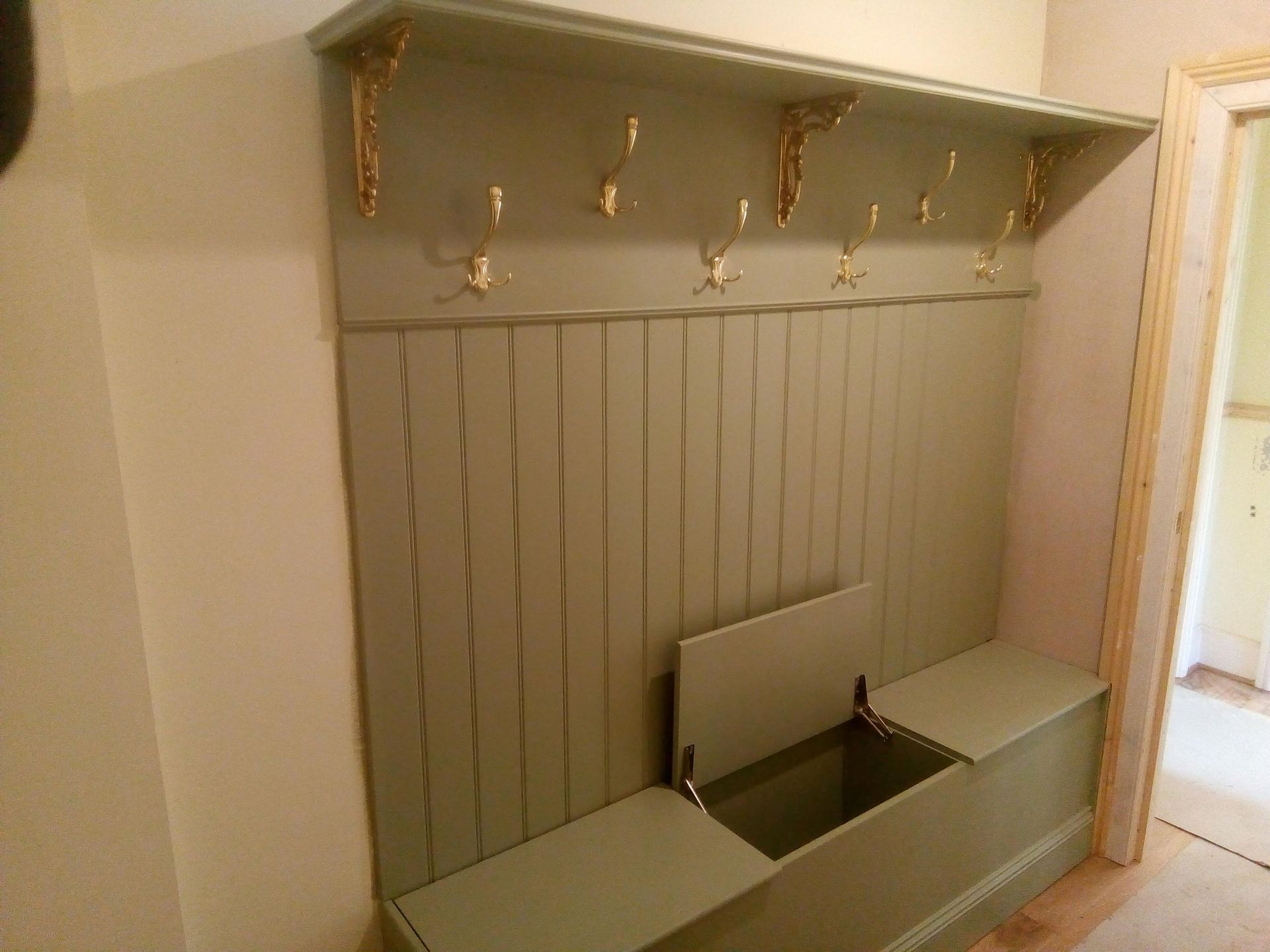 A hallway with a bench and a coat rack.