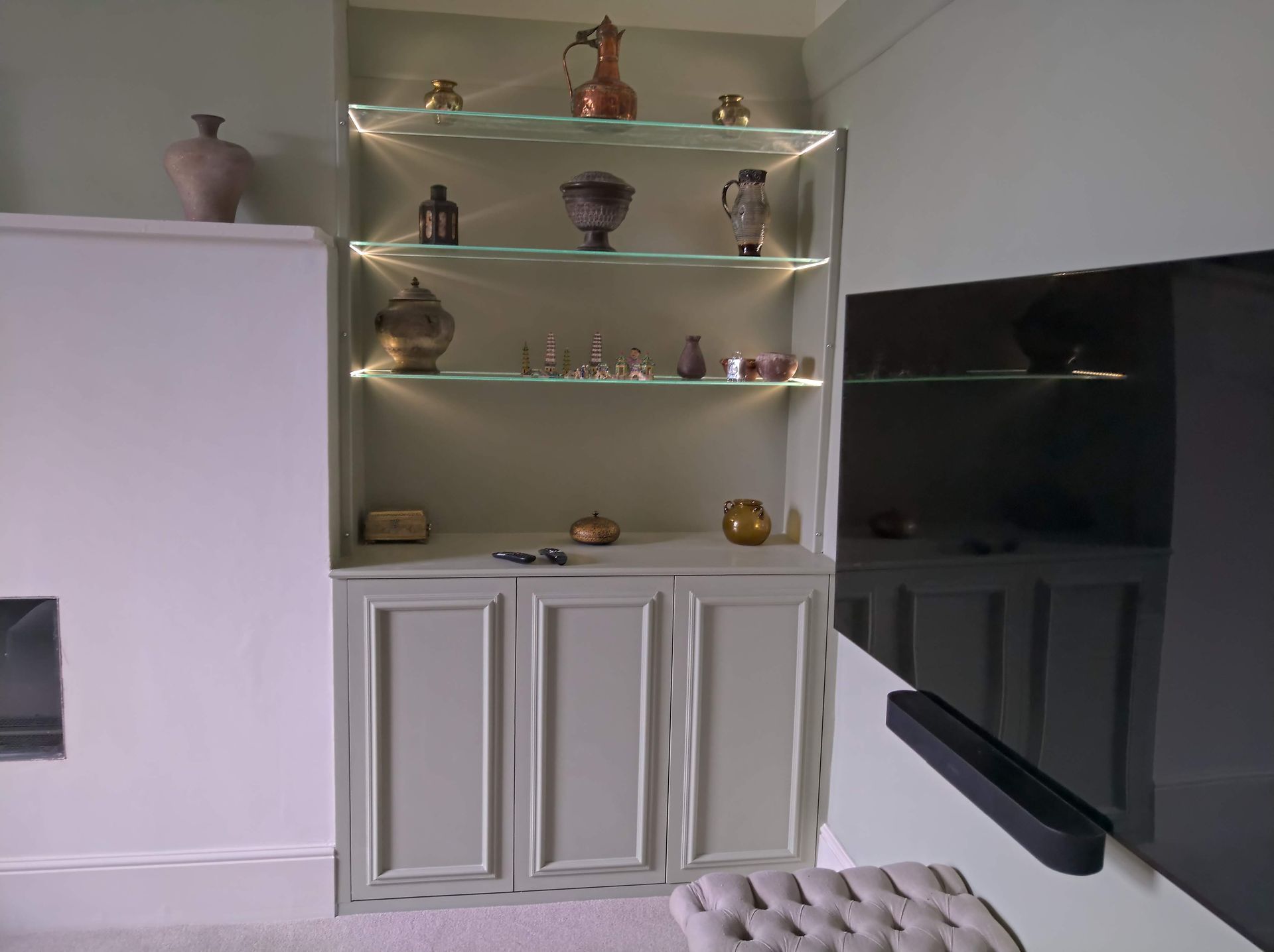 A living room with a tv and shelves with vases on them