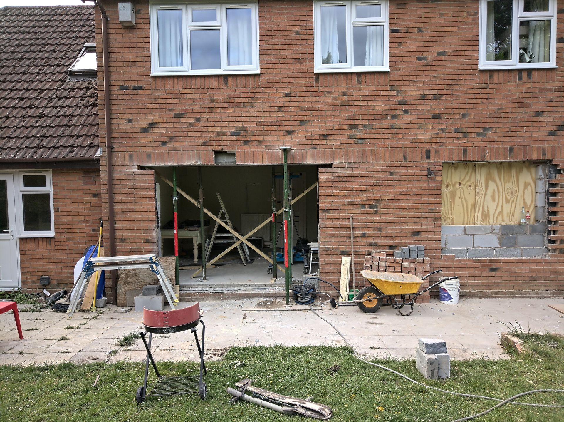 A brick house under construction with a wheelbarrow in front of it