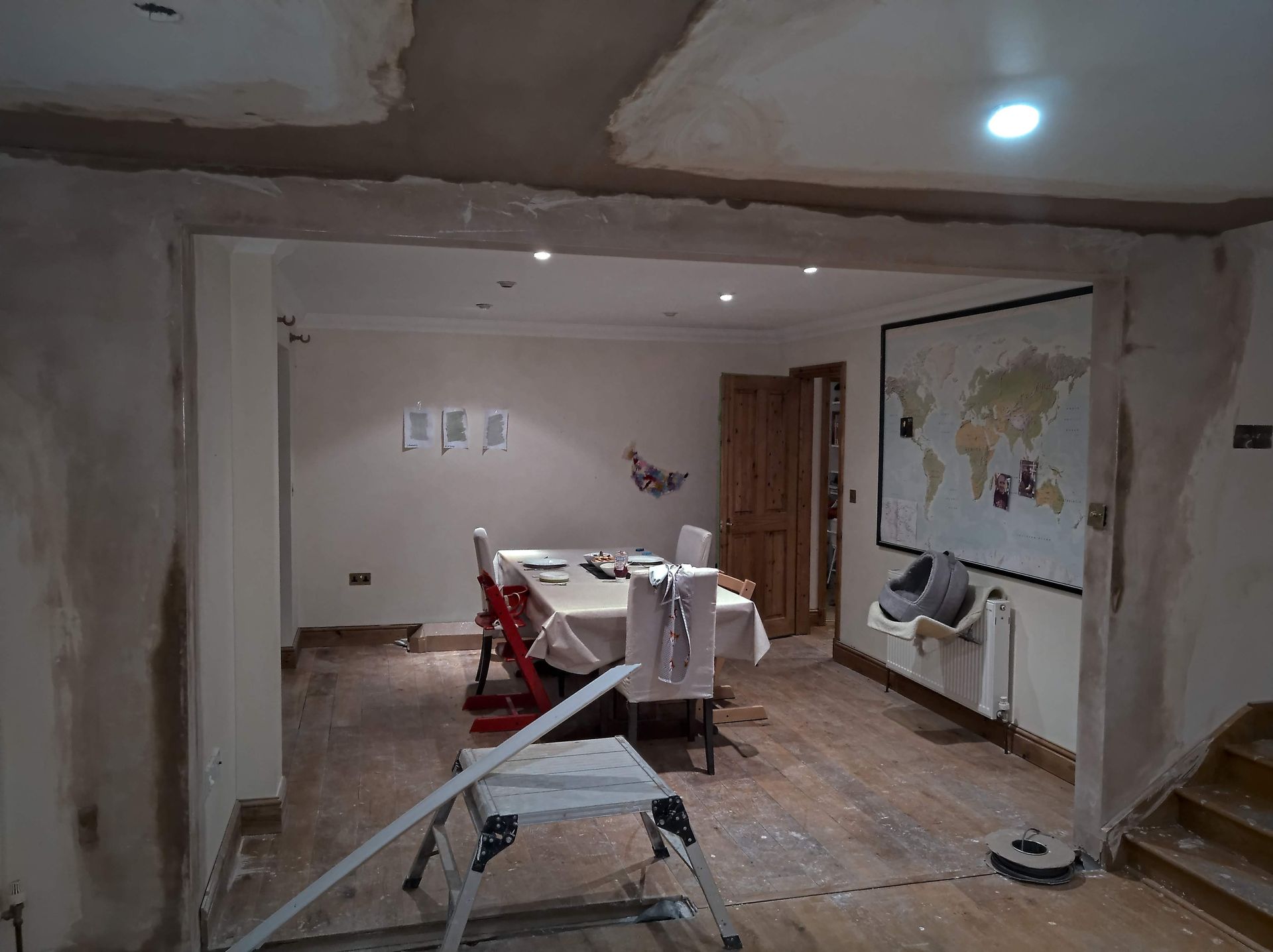 A dining room with a table and chairs and a map of the world on the wall.