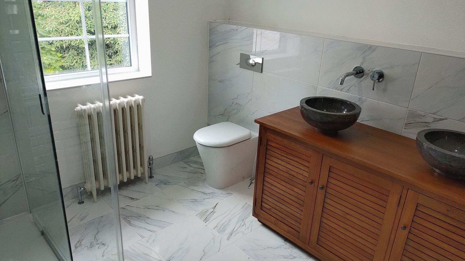 A bathroom with a toilet , sink and walk in shower.