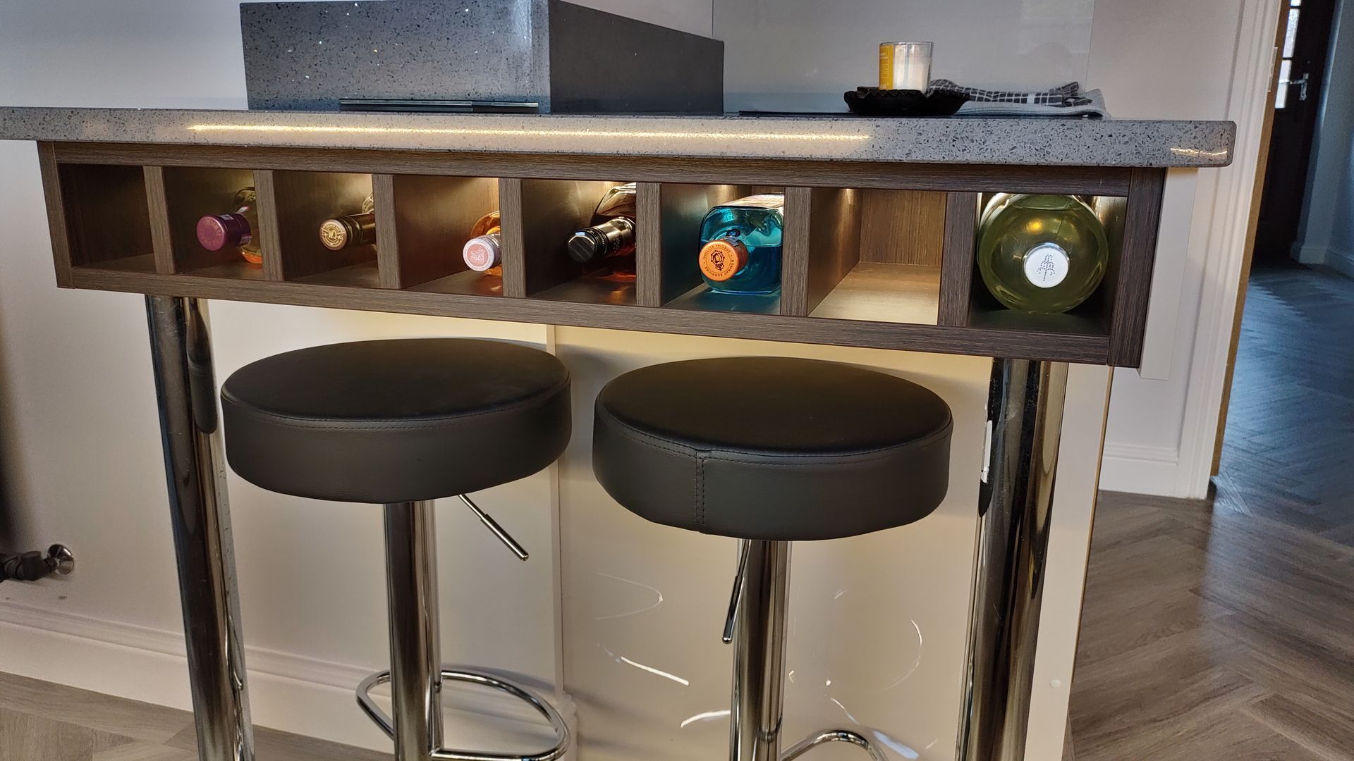 A bar with two stools and a wine rack on it.