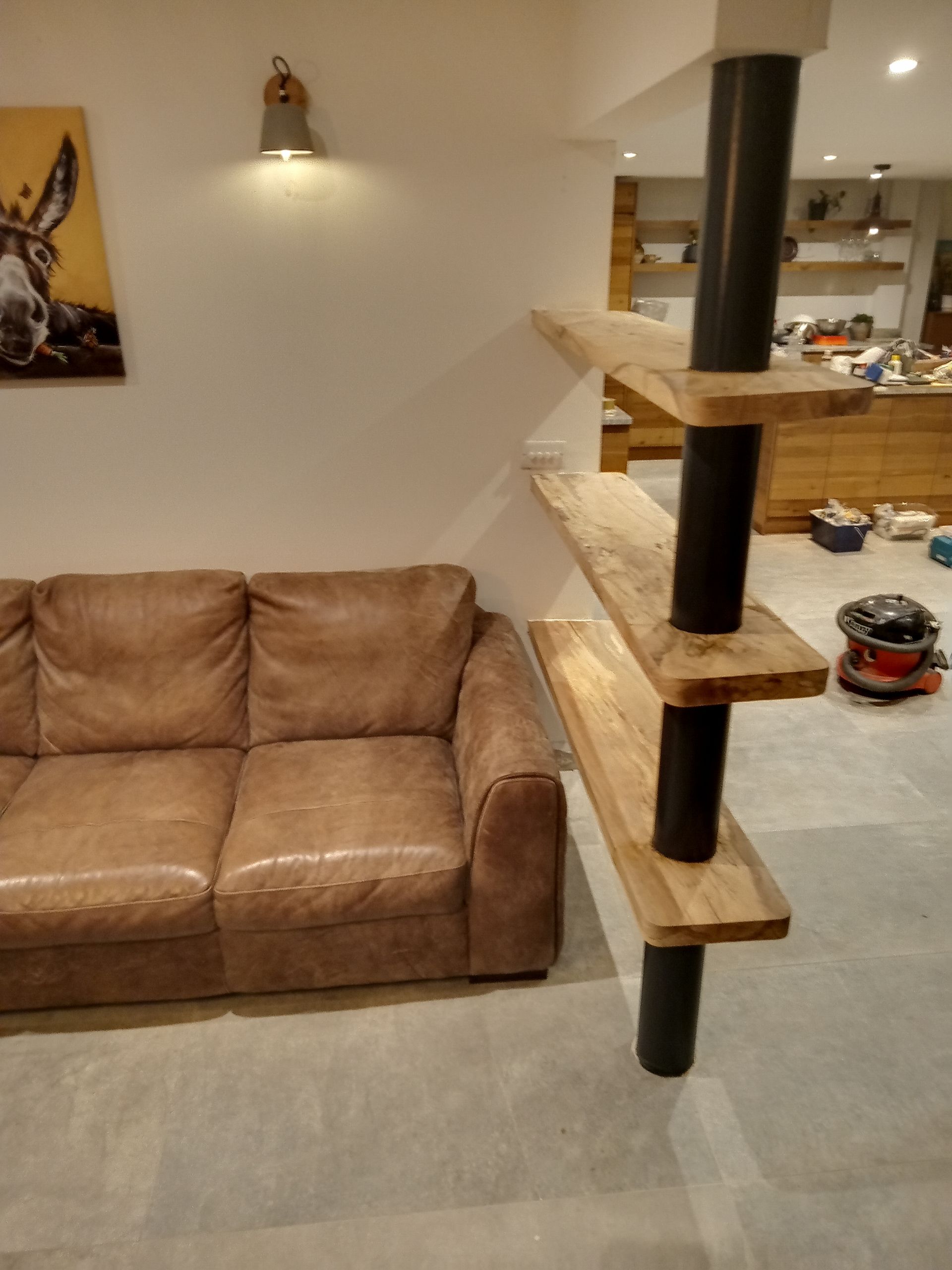 A living room with a brown leather couch and wooden shelves