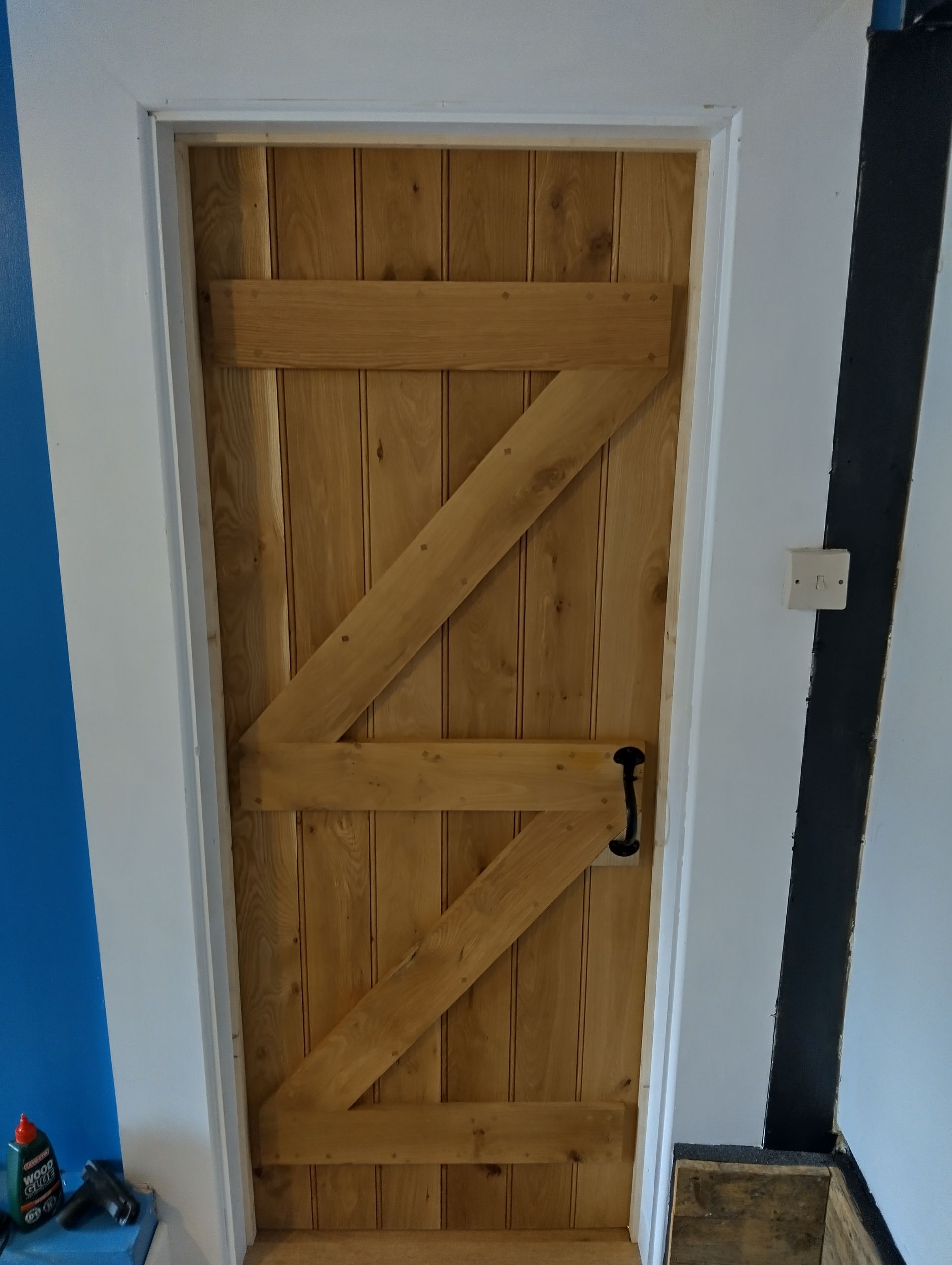 A wooden door in a room with a blue wall