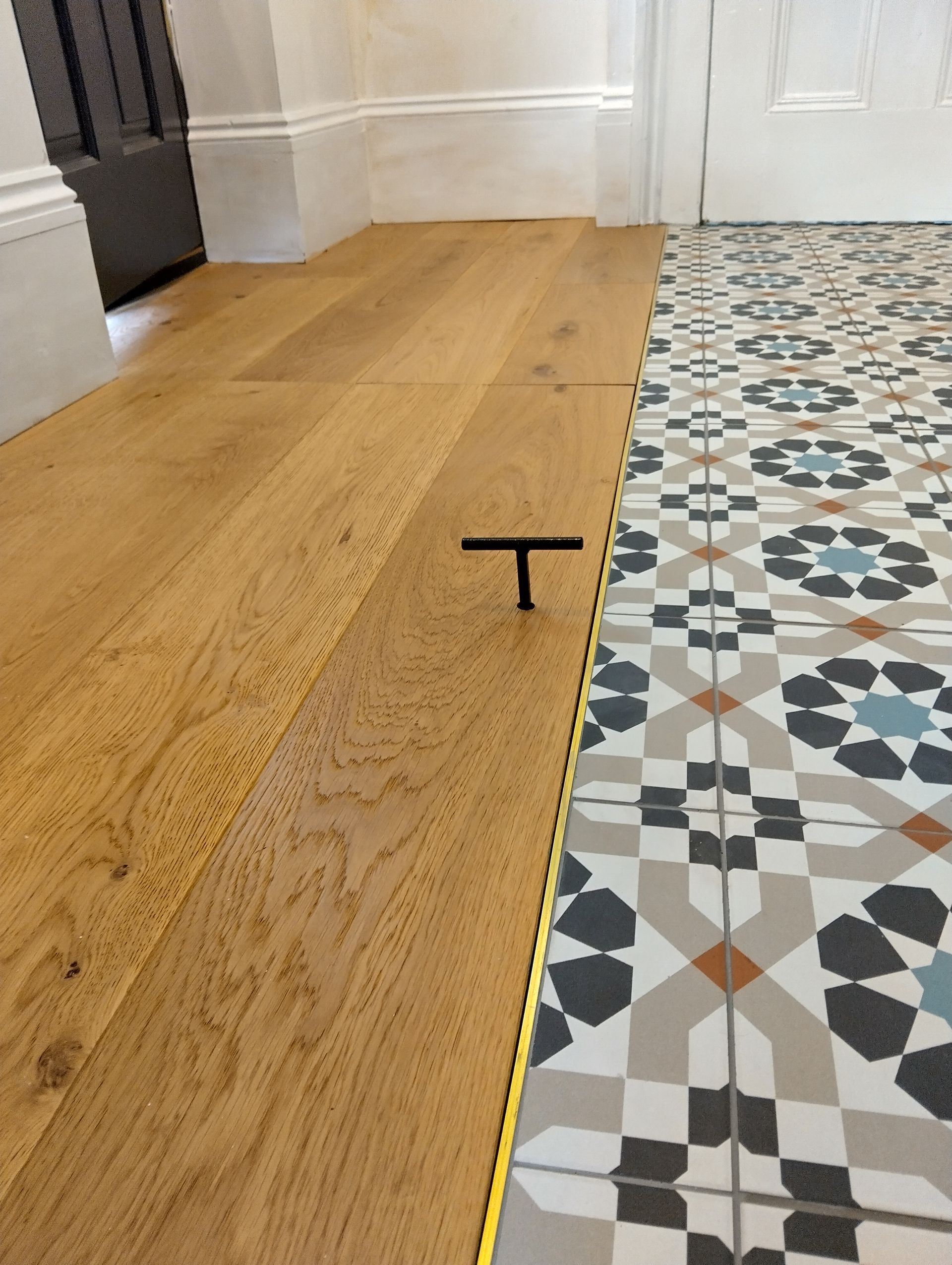A wooden floor with a tile floor in the background