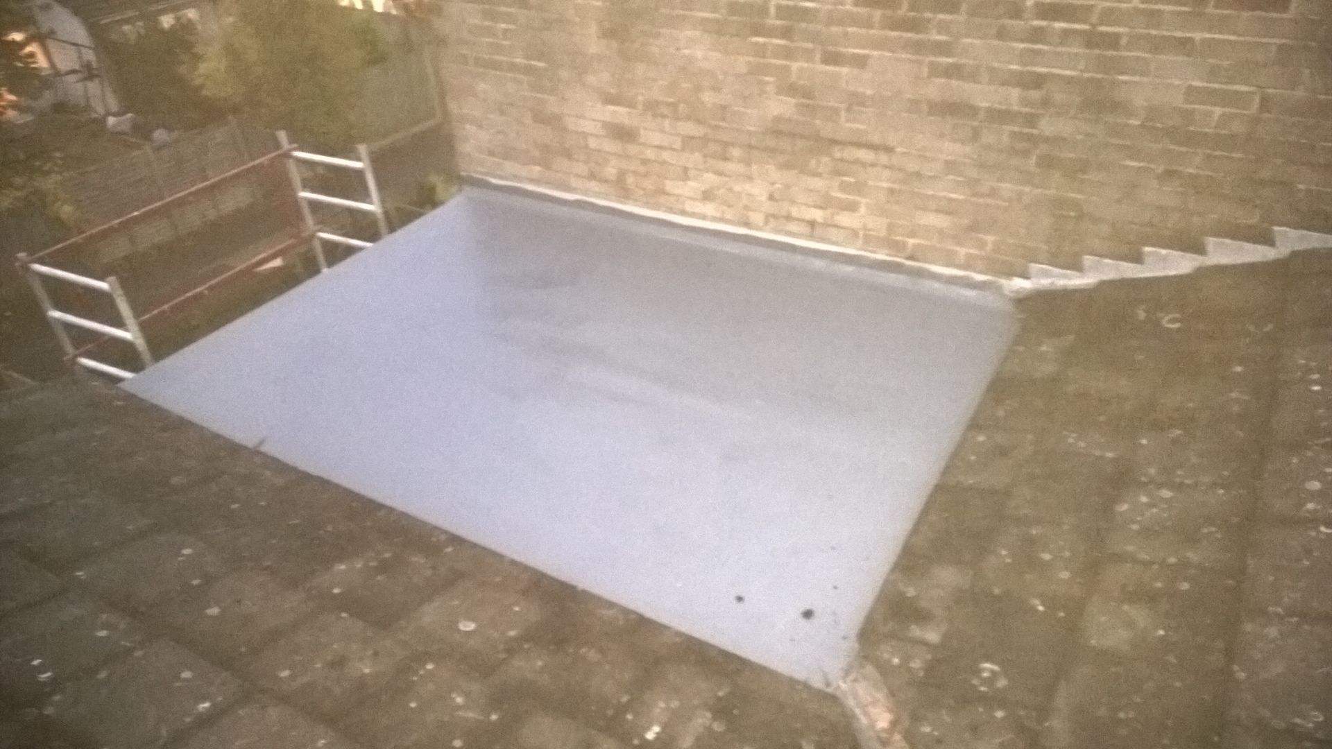 A brick wall with stairs leading up to it and a concrete floor in front of it.