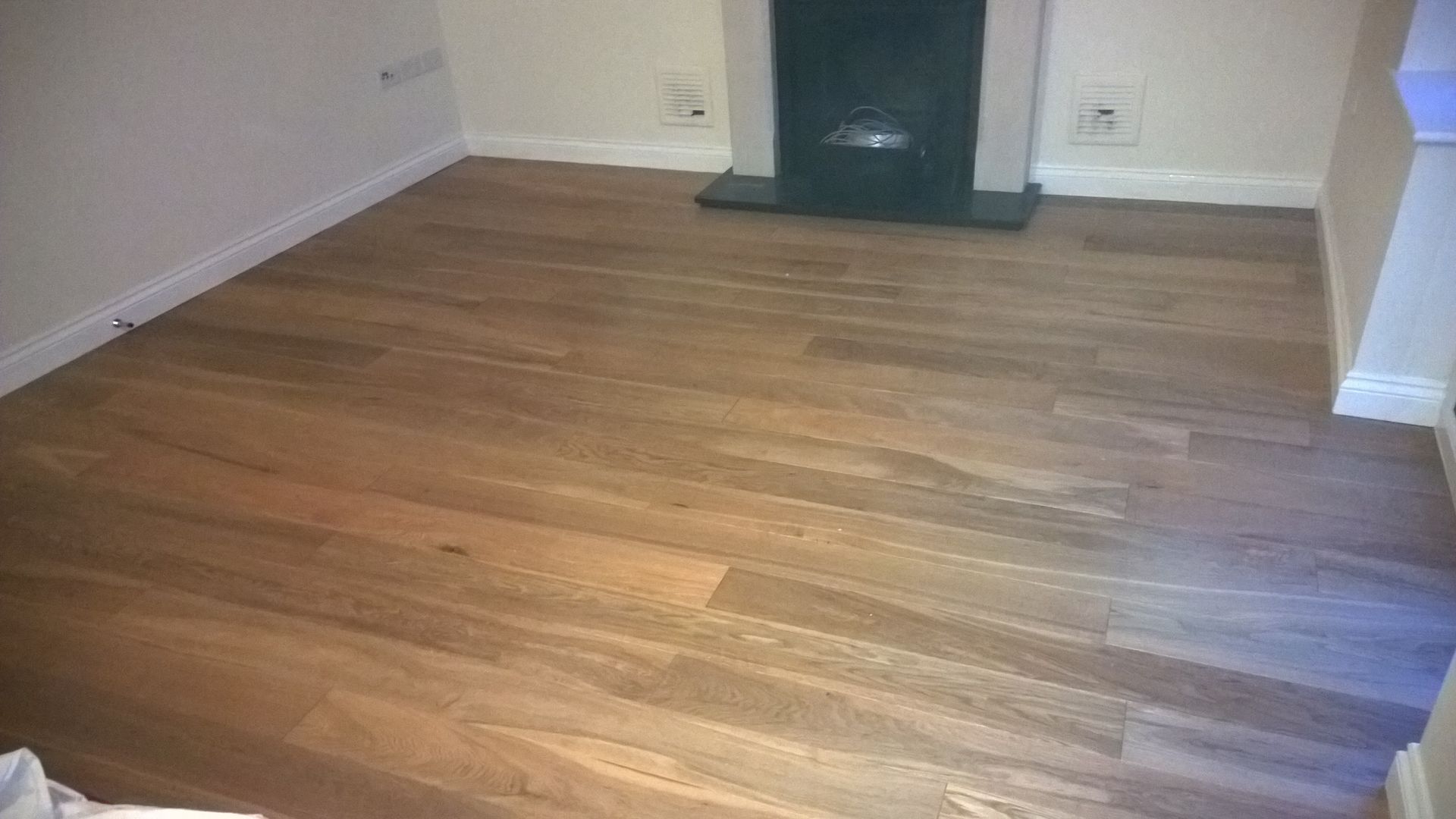 A living room with hardwood floors and a fireplace.