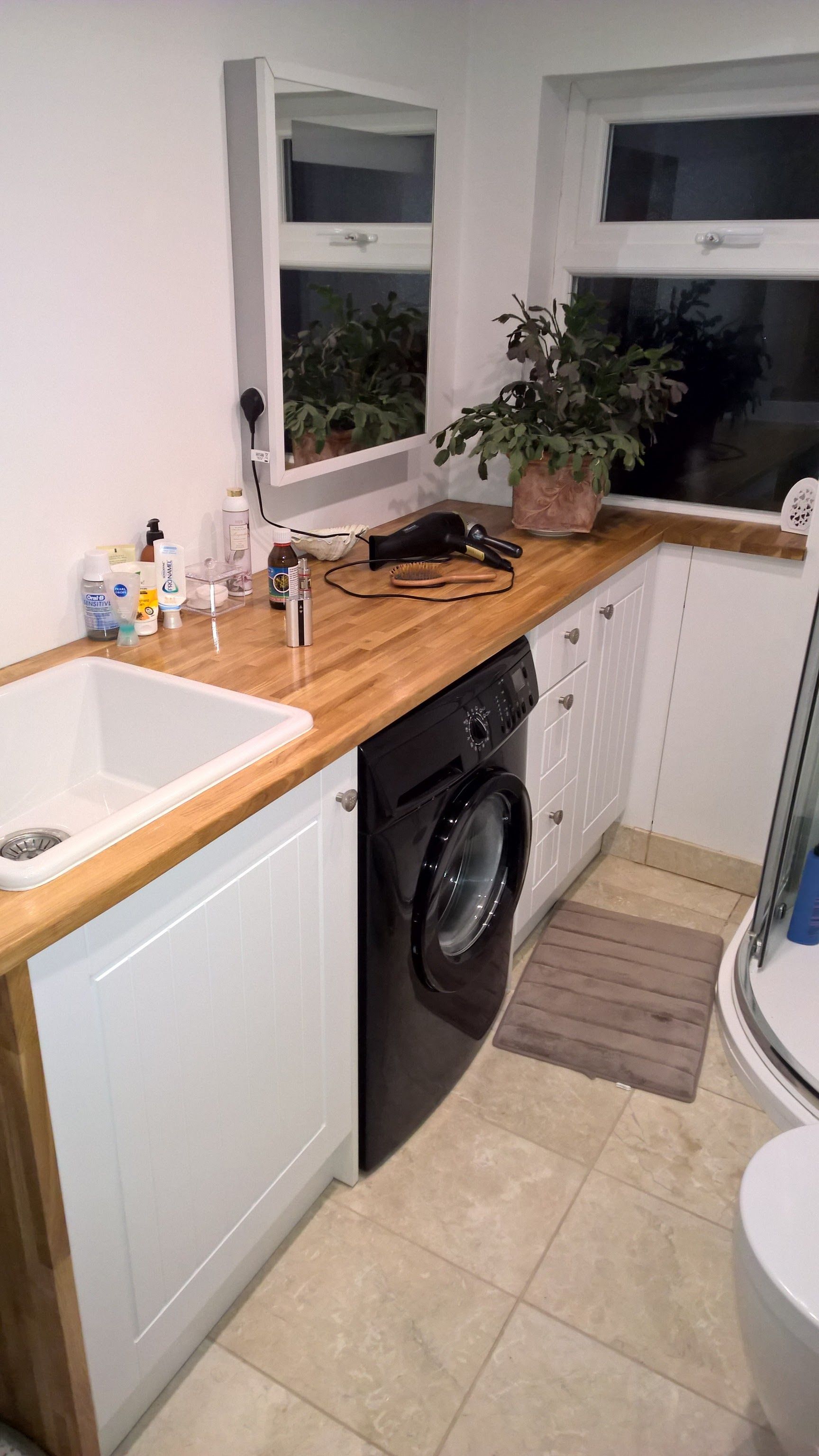 A bathroom with a sink , washing machine , and toilet.