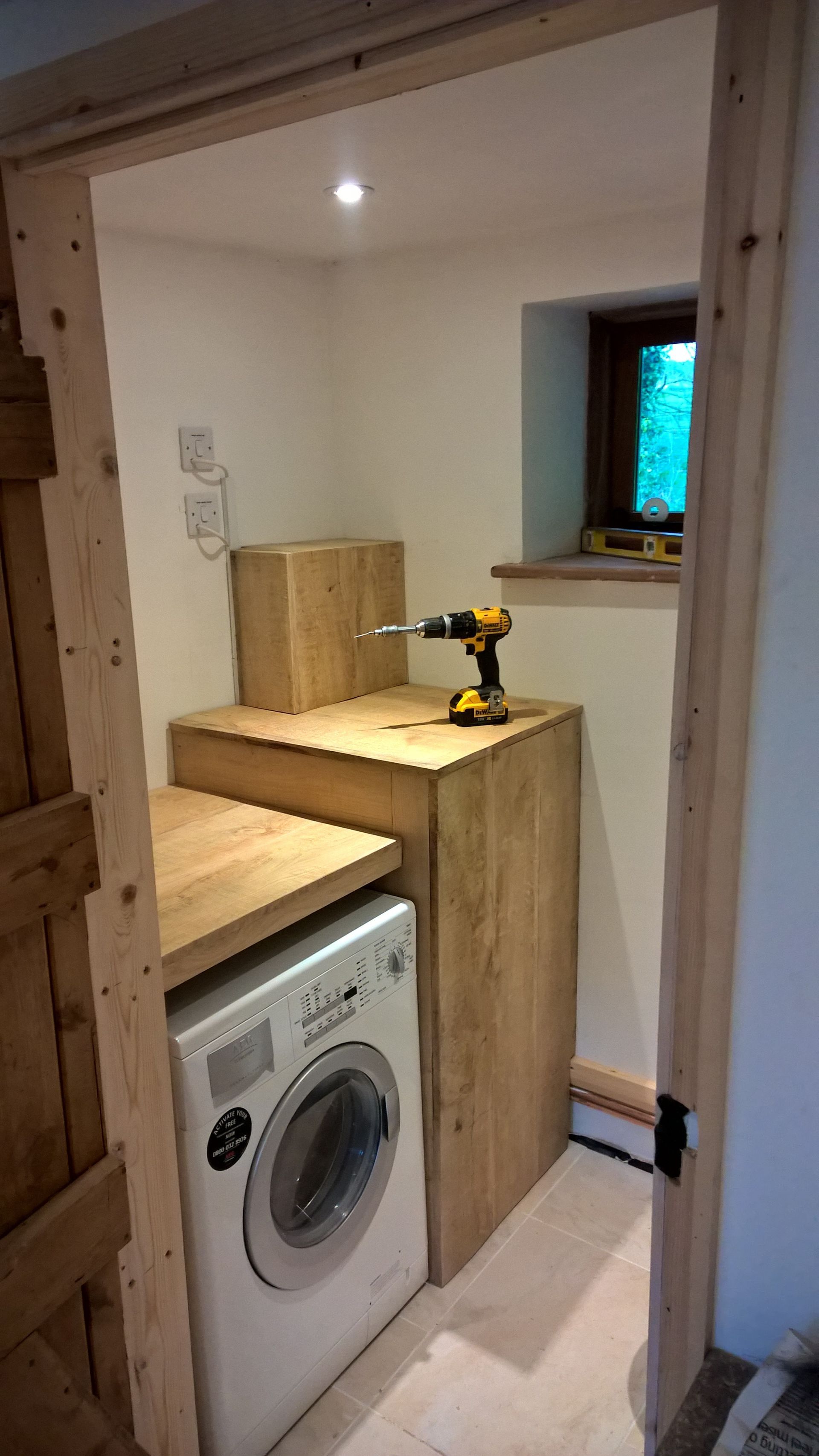 A washer and dryer are sitting on top of a wooden counter in a laundry room.