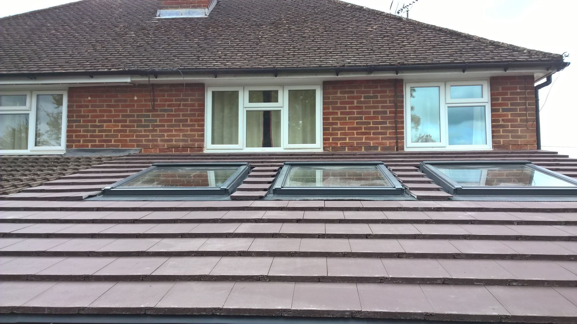 A brick house with three skylights on the roof.
