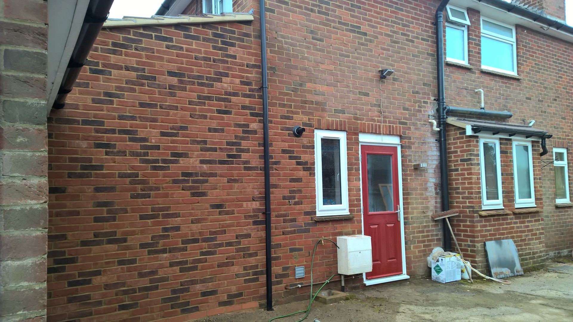 A brick house with a red door and white windows