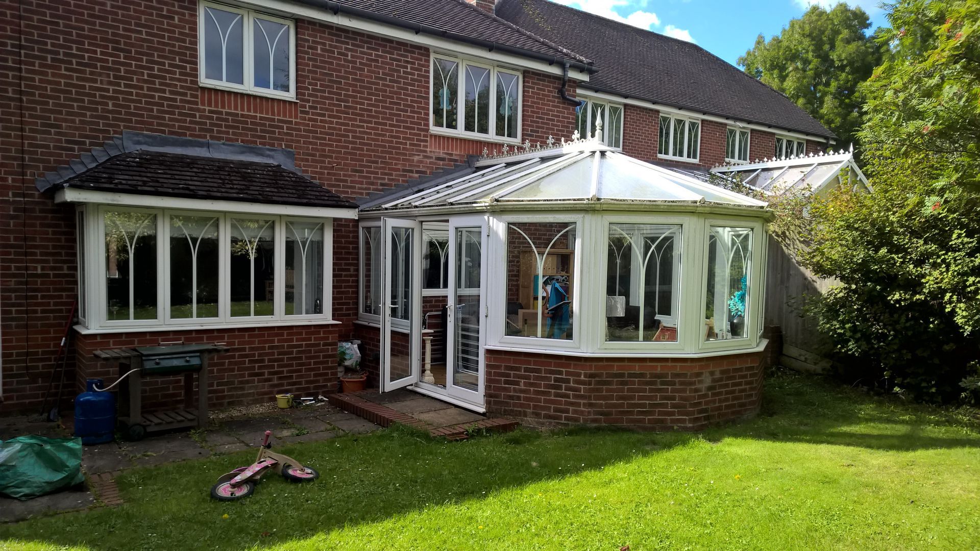 A brick house with a white conservatory in the backyard.
