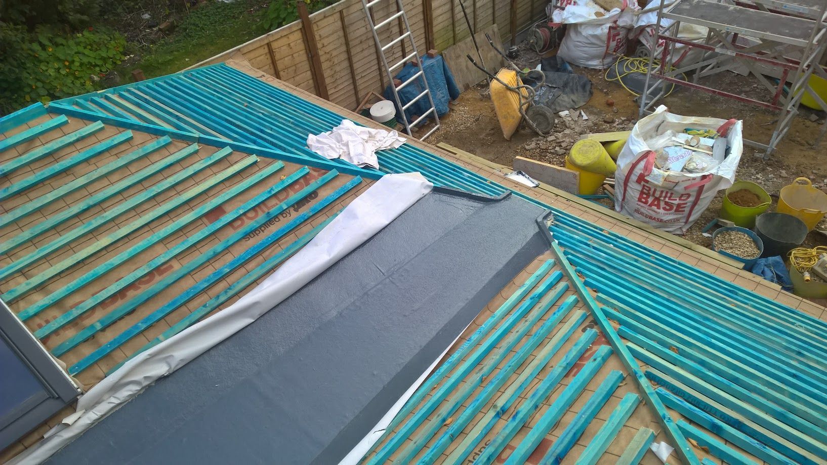 A roof is being built on a house with a ladder in the background.