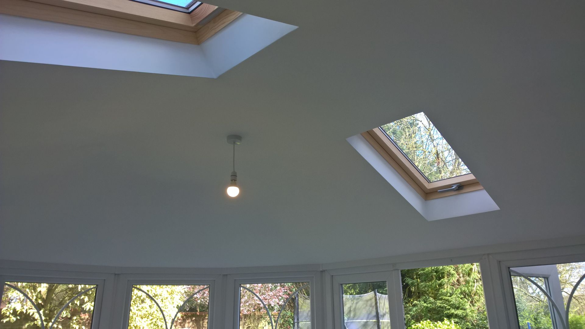 A room with two skylights and a light hanging from the ceiling
