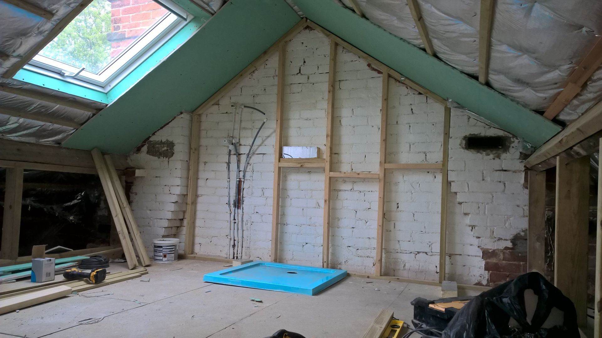 An attic with a skylight and a blue mat on the floor.