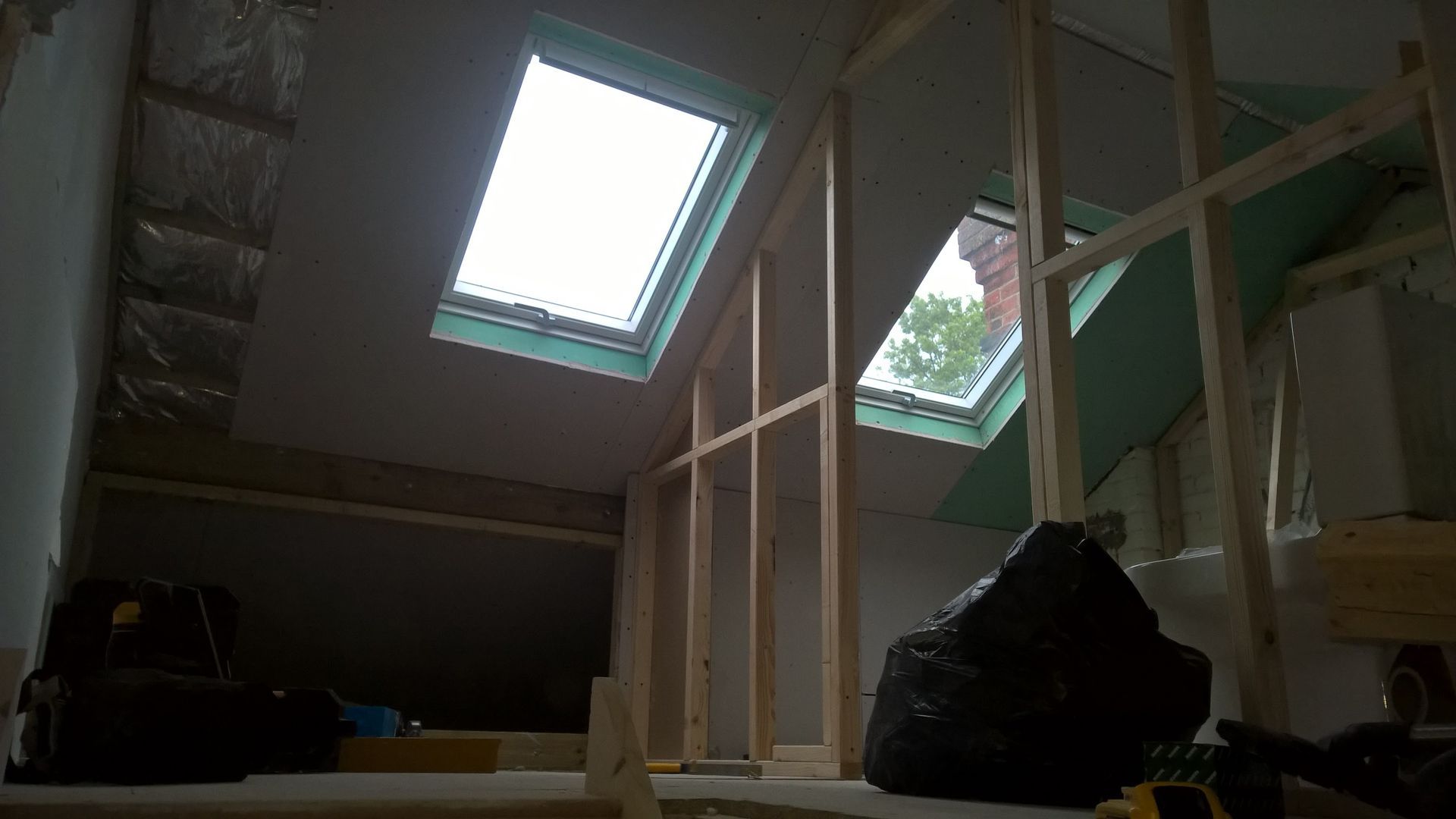 A room with two skylights and a black bag on the floor