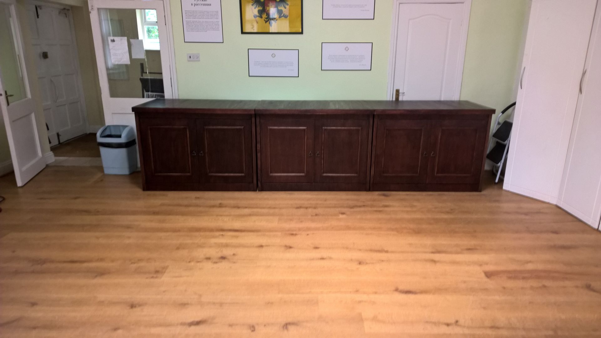 A wooden floor in a room with a desk and a trash can.