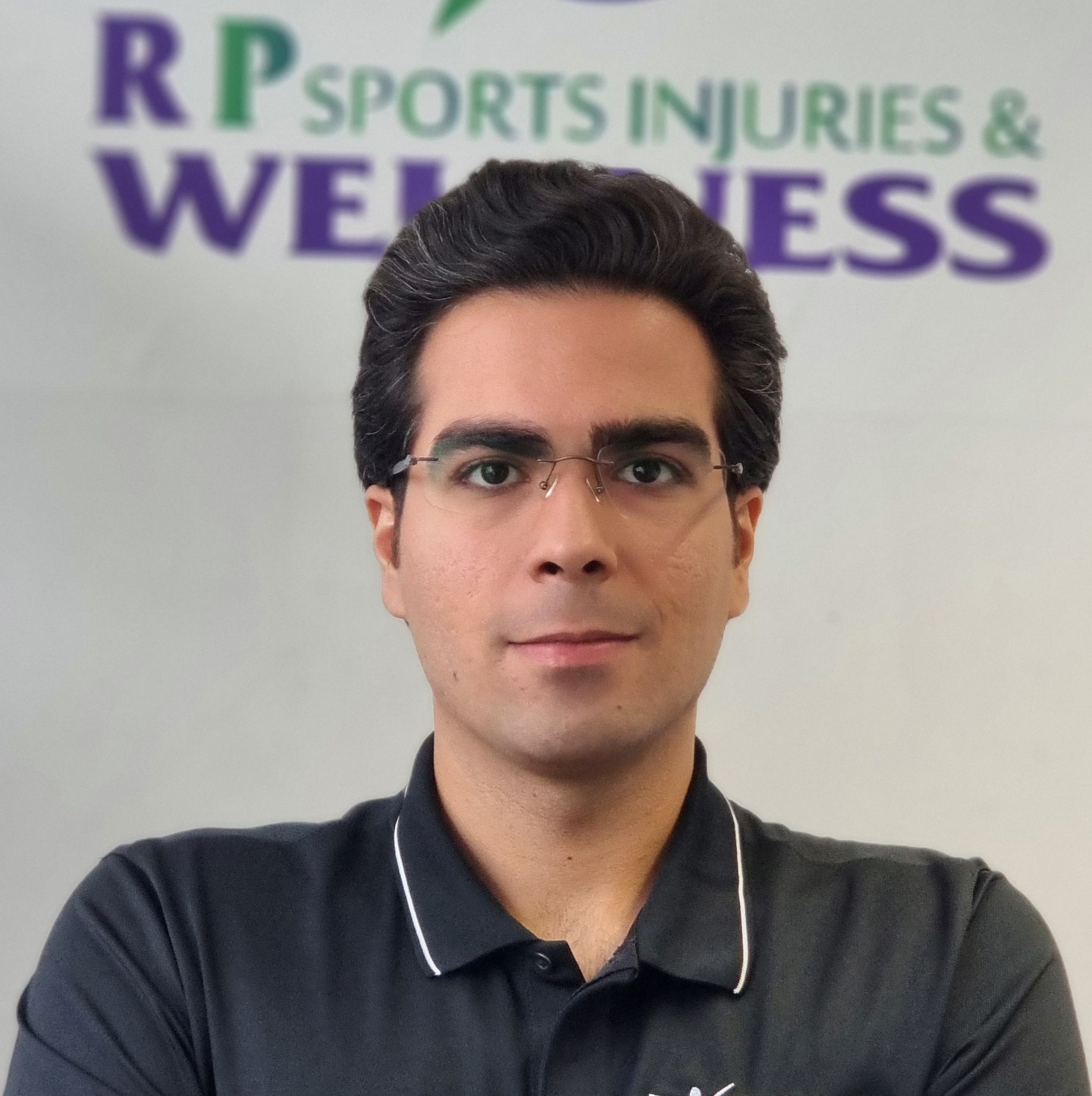 Mark, a dedicated Sports Therapist at Total Massage Clinic, wearing glasses and a black collared shirt with white trim, looks professional and composed against a clean white background.