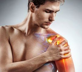 A young man holding his injured shoulder that's highlighted in red. Physiotherapy concept. Massage Therapy.