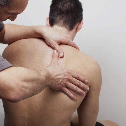 A therapist examining a man's right shoulder blade
