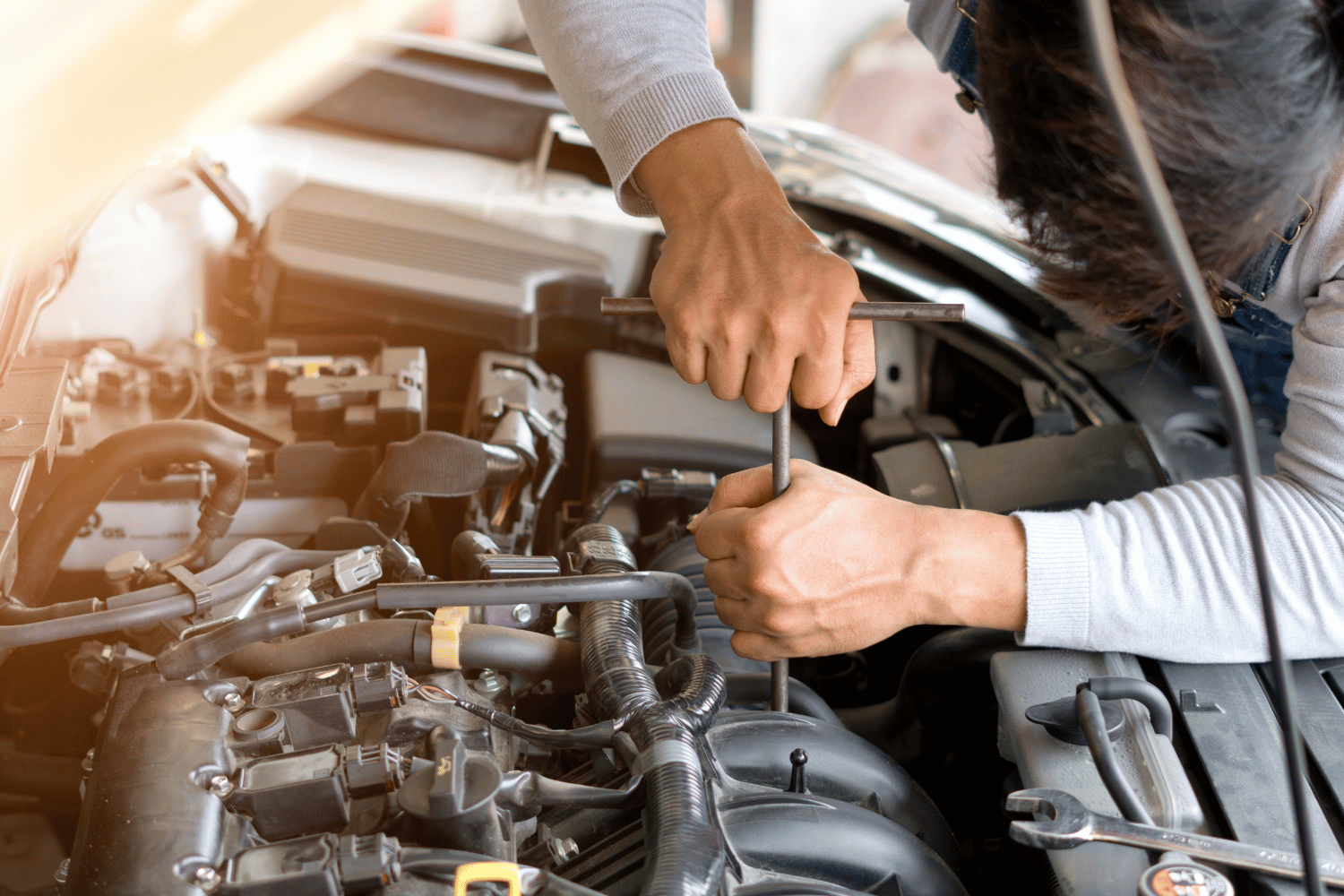 Person using a wrench to work on a car engine; hands visible.