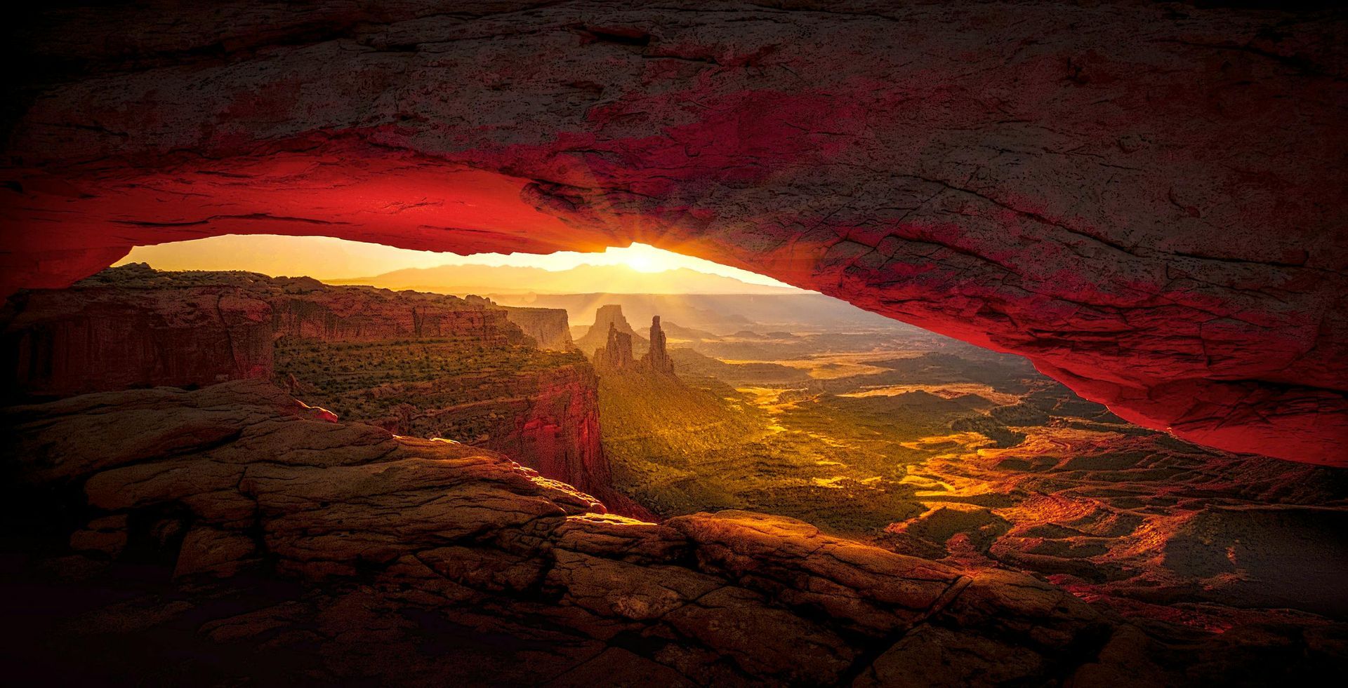 The sun is shining through the archway in the canyon.