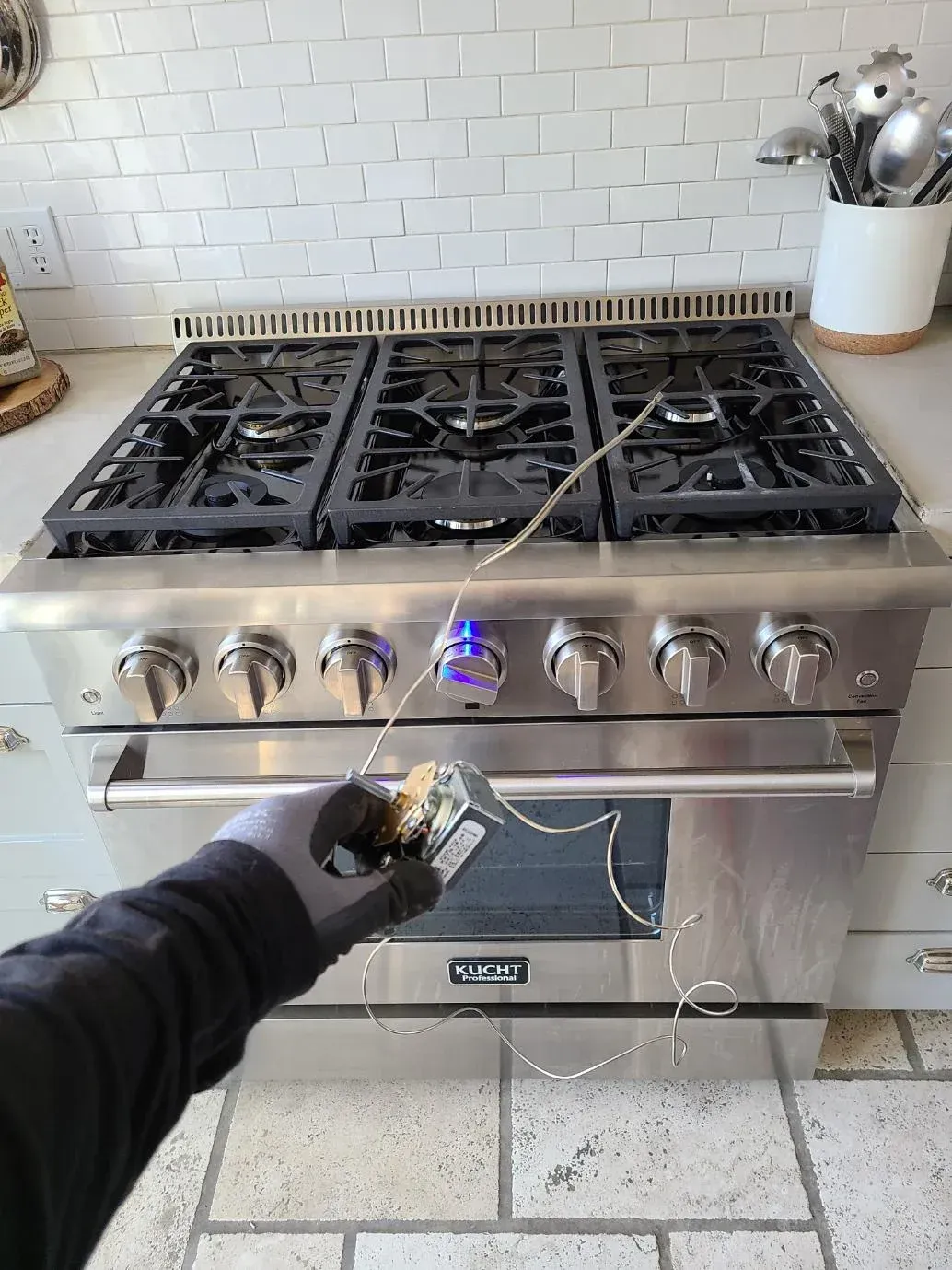 A person is cleaning a stove with a glove.