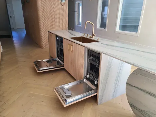 A kitchen with two dishwashers open and a sink.