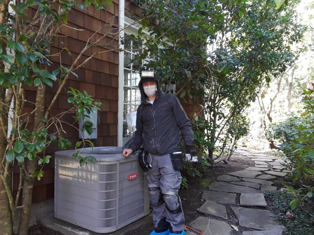 A man wearing a mask is standing next to an air conditioner outside of a house.