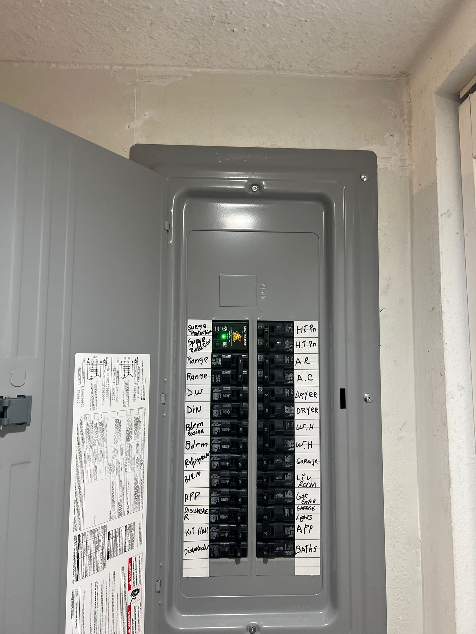 Man on ladder installing a woven light fixture on a white ceiling near a window.