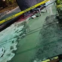 A cracked windshield, viewed from above, with yellow caution tape stretched across the upper frame.