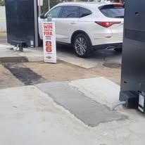 A white SUV is parked in front of a McDonald's drive-thru sign advertising a FIFA promotion at a concrete gas station.
