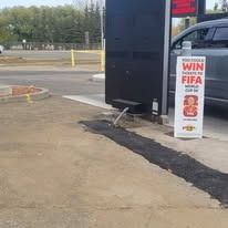 A drive-thru ordering screen at a restaurant next to a car, featuring a sign promoting a FIFA World Cup ticket contest.
