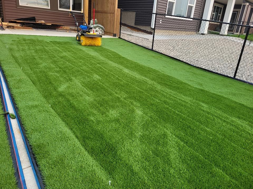 A patch of newly installed vibrant green artificial turf with a grass-seaming machine sitting in the background.