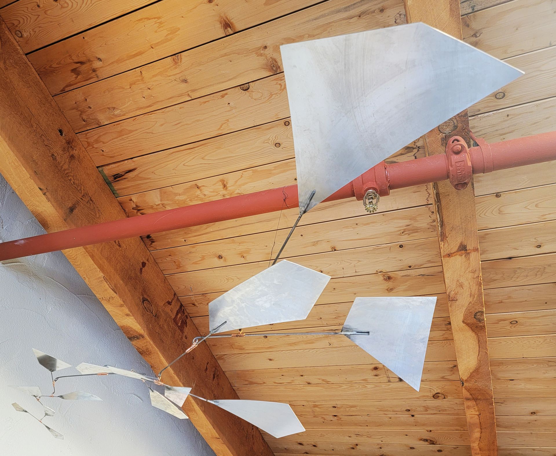 A wooden ceiling with a red pipe hanging from it