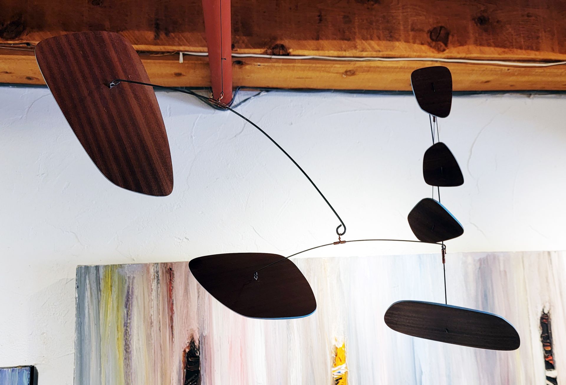 A mobile hanging from the ceiling in front of a painting