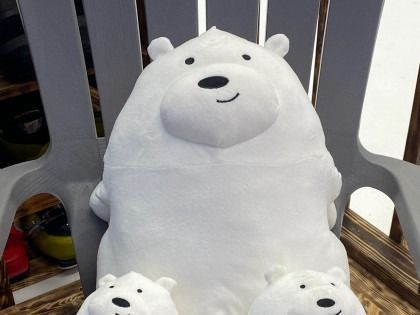White plush polar bear with small matching bear cubs sitting on a gray plastic chair.