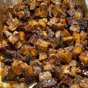 Close-up of a tray filled with tender, glazed, smoked beef brisket burnt ends, a barbecue dish.