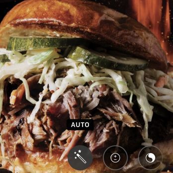 Pulled pork sandwich with coleslaw and pickles on a toasted bun.