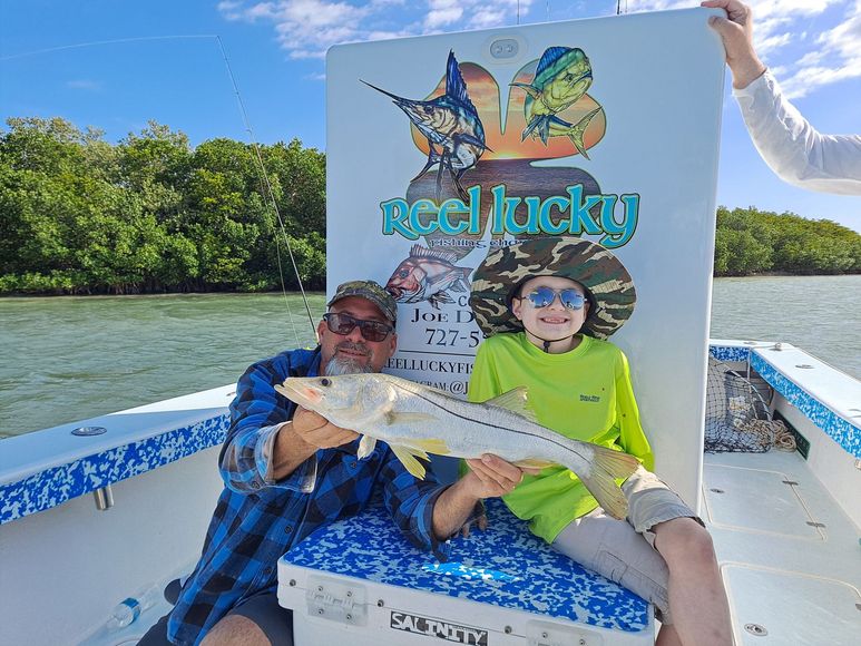 Man and child on a boat holding a fish. They're smiling in front of a 