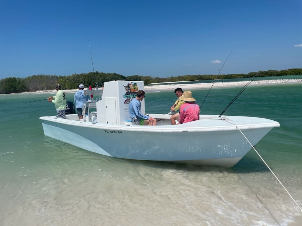 People fishing from a light blue boat on a sunny beach.